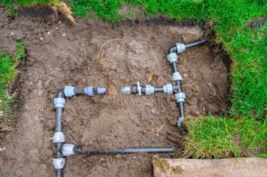 Plastik borular ve çim sulama için elektrik tesisatı. Bahçedeki suyu kesmek için bağlantı tesisatları ve vanalar
