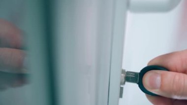 Anahtar kötü bir şekilde kilitten çıkarılmış, yakın plan. Delinmiş bir anahtar, beyaz plastik kapıların anahtar deliğine yerleştirilir. Yüksek kalite 4k görüntü