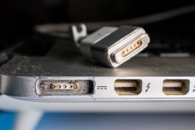 Kyiv, Ukrayna - 16 Ağustos 2023: Eski bir Apple MacBook Pro Retina üzerinde eritilmiş bağlantıları olan magsafe 2 teknolojisi ile şarj olmak için mıknatıs ile bir bağlantı