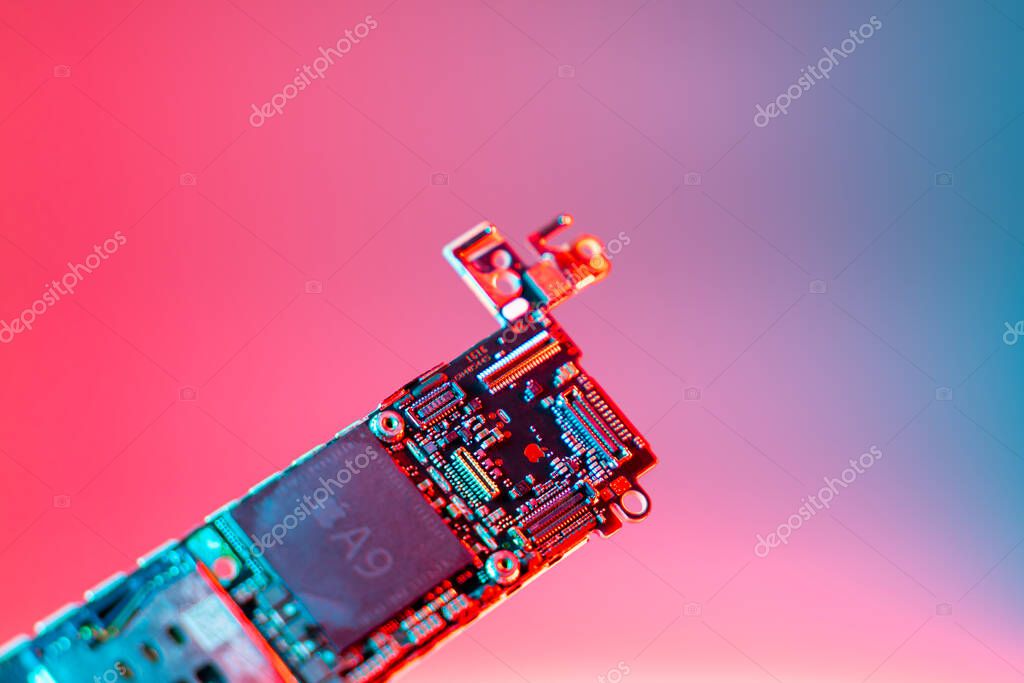 Kyiv, Ukraine - August 25, 2023: iPhone SE motherboard with Apple A9 processor, close-up on a rich color background. Gold company logo on the phone board