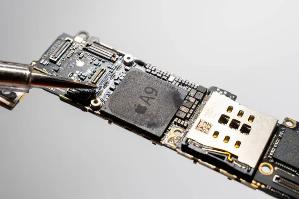 Kyiv, Ukrayna - 25 Ağustos 2023: Apple A9 işlemcili ana kart ve bir tornavida, yakın çekim. iPhone SE çipli tahta hizmette