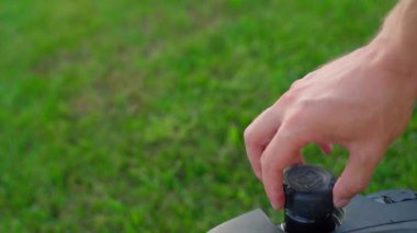 Çim biçme makinesinde depo dolusu benzin. Bir el, yeşil çimenlerin arka planına karşı bir benzin deposu kapağını vidalıyor. Yüksek kaliteli FullHD görüntüler