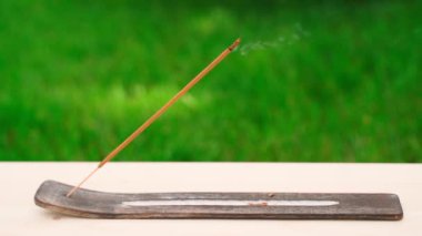 Bir tezgahtaki tütsü çubuğu, yeşil çimenlerin arka planına karşı sigara içer, yakın plan. Meditasyon seti. Yüksek kaliteli FullHD görüntüler