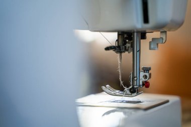 Dikiş makinesi iğnesi iplikle, bulanık arkaplanda yakın plan