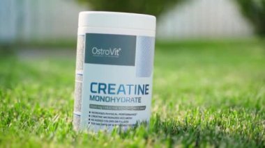 Kyiv, Ukrayna - 29 Ağustos 2024: OstroVit firmasından gelen kreatin içeren karpuz aromalı monohidrat, yeşil çimlere yakın plan, gün batımı. Yüksek kaliteli FullHD görüntüler