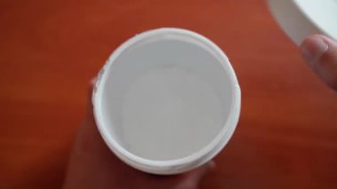 Kyiv, Ukrayna - 25 Eylül 2024: Kreatin monohidratla plastik bir kavanoz açmak ve bir kepçe dolusu barutu yakın plan çekmek. Spor beslenme resepsiyonu. Yüksek kalite 4k görüntü