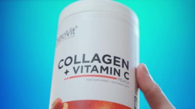 Kyiv, Ukrayna - 4 Ocak 2025: Kolajen ile plastik kavanoz ve şeftali aromalı C vitamini ve bulanık arkaplan üzerine yakın çekim. Yüksek kalite 4k görüntü