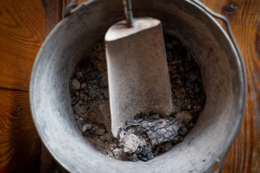 Şöminenin külleri ve külleri temizlemek için bir kepçe olan demir kovanın yakın çekimi..