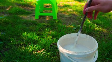 Ağaç gövdelerini kovada tedavi etmek için karıştırma sıvısı, yakın plan. Güneşli bir yaz gününde bahçede bakım için hazırlanıyorum. Yüksek kalite 4k görüntü