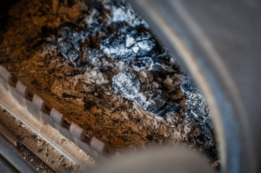 Yanmış külle şömine, yakın plan. Kır evinde ahşap ısıtma.