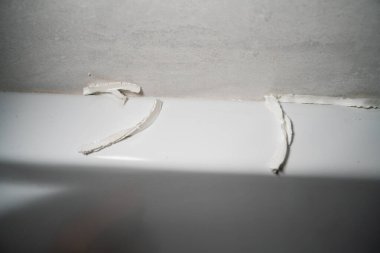 Duş kabininde düşük kalitede beyaz dolgu macunu var. Yerine koymak için dolgu macunu çıkarılıyor ve nemden korunmak için taze dolgu macunu uygulanıyor.