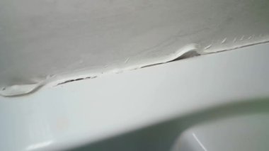 Duş sehpası ve duvarın birleşme yerindeki dolgu maddesi soyulmuş, yakın plan. Kalitesiz beyaz dolgu maddesi. Yüksek kaliteli FullHD görüntüler