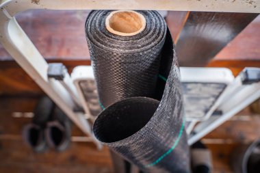 Siyah takviyeli agrofiber yakın çekim. Toprağı yabani otlardan korumak için güçlendirilmiş film..