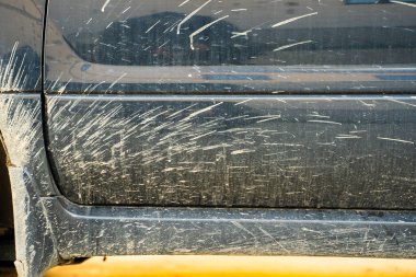 Araba, tekerleklerin altından fırlatılan çamurla kirlenmiş.