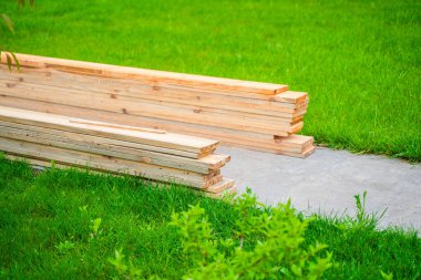 İnşaat için ahşap tahtalar yeşil çimlerin üzerine yığılmış, yakın plan..
