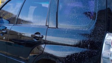 Siyah araba yüksek basınçlı çamaşır makinesiyle yıkanmış, yakın plan. Yüksek kaliteli FullHD görüntüler