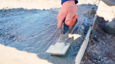 Bir adamın eli, yavaş çekimde bir malayla taze betonu düzleştiriyor. Yüksek kaliteli FullHD görüntüler