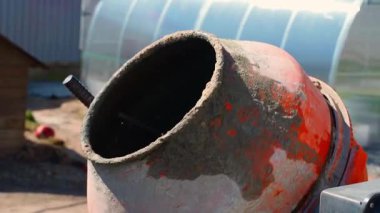 Güneşli bir günde küçük bir inşaat beton karıştırıcısı yakın planda dönüyor. Yüksek kaliteli FullHD görüntüler