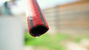 Bulanık arka planda, hortumdan damlayan bir damla su. Yüksek kaliteli FullHD görüntüler