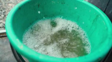 Suyu yeşil bir kovaya boşaltın, yavaş çekimde yakın çekim. Yüksek kaliteli FullHD görüntüler