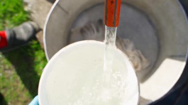 Beyaz bir kovada su topluyorum. Güneşli bir gün. Yüksek kaliteli FullHD görüntüler