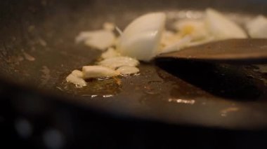 Soğanlar tavada kızartılıyor, yakın plan. Soğanları ahşap bir spatulayla karıştırmak, ağır çekim. Yüksek kaliteli FullHD görüntüler