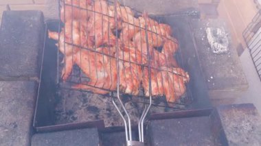 Izgaranın üstündeki tavuk kanatlarıyla ızgarayı çeviriyorum. Yüksek kaliteli FullHD görüntüler