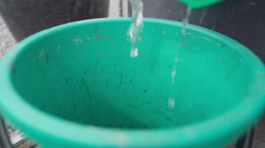 Su yeşil plastik kovaya dökülüyor, yavaş çekimde. Yüksek kaliteli FullHD görüntüler
