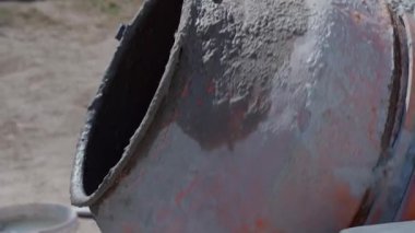 Kirli turuncu bir beton karıştırıcı dönüyor ve içine kum ve çakıl dolu bir kürek atılıyor. Yüksek kaliteli FullHD görüntüler