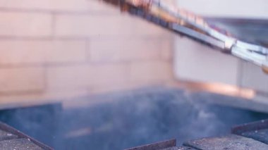 Tavuk butları ızgaranın üstünde dumanla pişiriliyor, yakın plan. Yüksek kalite 4k görüntü