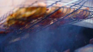 Tavuk butları ızgaranın üstünde dumanla pişiriliyor, yakın plan. Yüksek kalite 4k görüntü