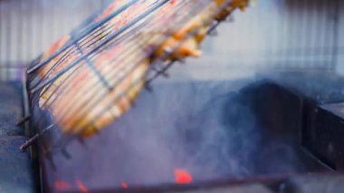 Tavuk butları ızgaranın üstünde dumanla pişiriliyor, yakın plan. Yüksek kalite 4k görüntü