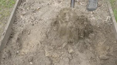 Yavaş çekimde, bir adam bahçe yatağında kürekle toprağı kazıyor, yakın plan. Açık havada fiziksel çalışma. Yüksek kaliteli FullHD görüntüler