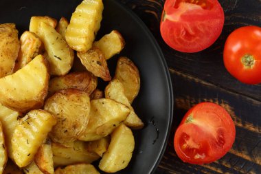 Siyah tabakta kızarmış patates. Domatesli ev yapımı kızarmış patates.