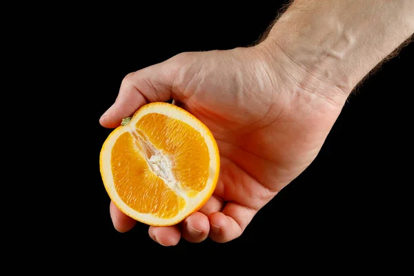 Cut orange in hand close-up isolate