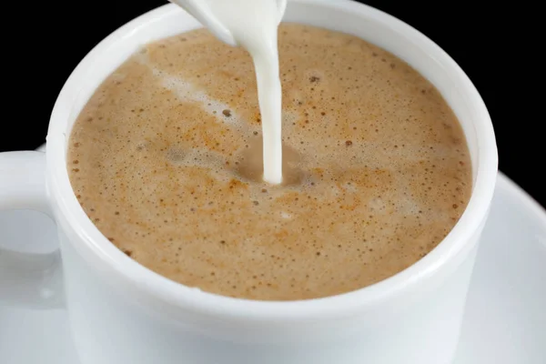 Coffee with milk. Milk is poured into a cup with coffee.