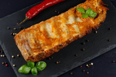 Fesleğenli ve baharatlı pirzola. Köhne ahşap masa, bir tava sulu pirzola, et ve baharatla.