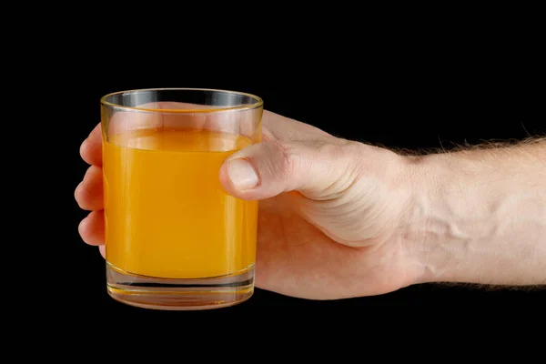 Orange juice in a glass in hand. Hand holding juice.