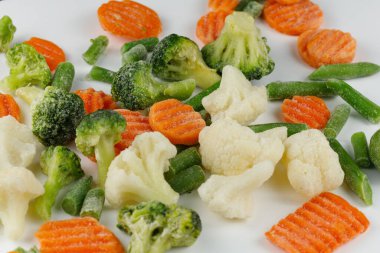 Donmuş sebzeler beyaz arka planda yakın plan çekimleri.