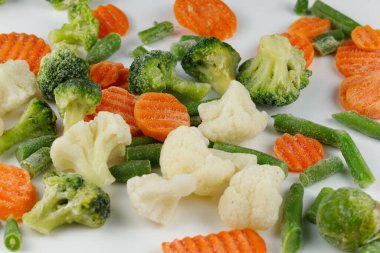 Donmuş sebzeler beyaz arka planda yakın plan çekimleri.