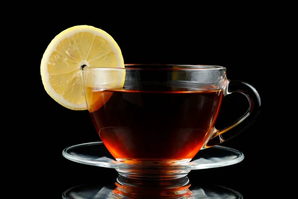 Tea with lemon in a cup. Cup tea with lemon. Black tea with a slice of lemon in a glass mug