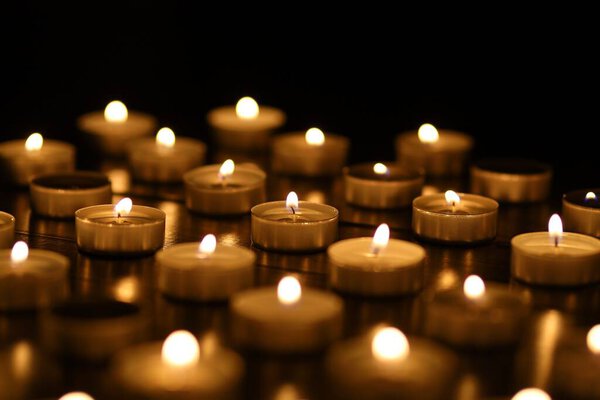 Small candles burning on a dark background. Bight Lights of candle. place for text cope space