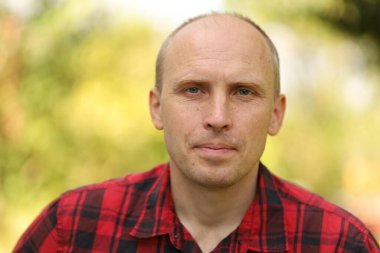 Kırmızı kareli gömlekli yakışıklı beyaz bir adam.