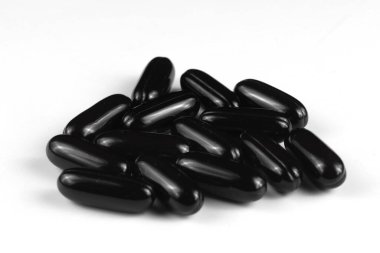 Siyah jel kapsülleri beyaz bir yüzeye saçılmış..