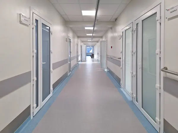LVIV, UKRAINE - 25 Mart 2024: Kapalı kapılar ve uzak figürlerle temiz, parlak hastane koridoru.