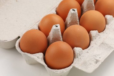 Gri bir karton yumurta kutusunda bir düzine taze kahverengi yumurta..