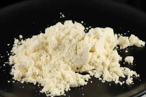 Protein supplement powder heap on a dark background.