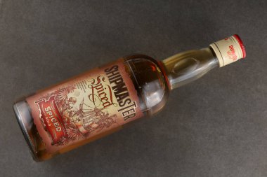 LVIV, UKRAINE - 22 Mayıs 2024: Shipmaster Baharatlı Rom şişesi karanlık bir yüzey üzerinde yatay olarak yatar, eski etiketini vurgular.