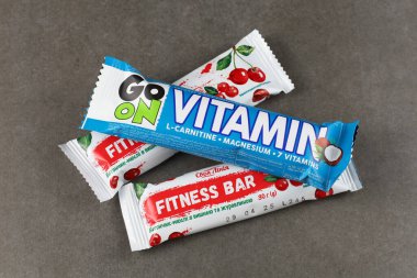 LVIV, UKRAINE - 25 Haziran 2024: kiraz aromalı ve mavi vitaminli barlar, gri bir yüzeye dizilmiş, farklı ambalaj tasarımlarını vurgulayan.