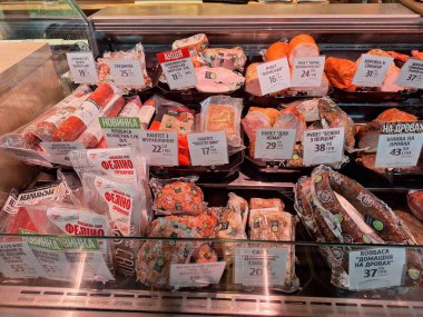 LVIV, UKRAINE - 10 Temmuz 2024: Süpermarkette bir şarküteri tezgahı, çeşitli yeni hazırlanmış et ve sosislerle dolu. Etler temiz plastik ambalajlarda sergileniyor ve her ürünün üzerinde fiyat etiketleri görülüyor. Etler füme sosis içeriyor.